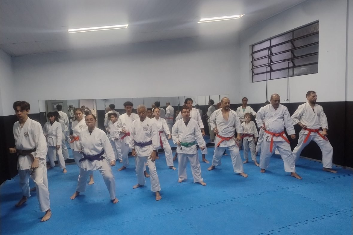 Turma de crianças, jovens e adultos treinando kihon lado a lado no tatame do CEE Cambuci